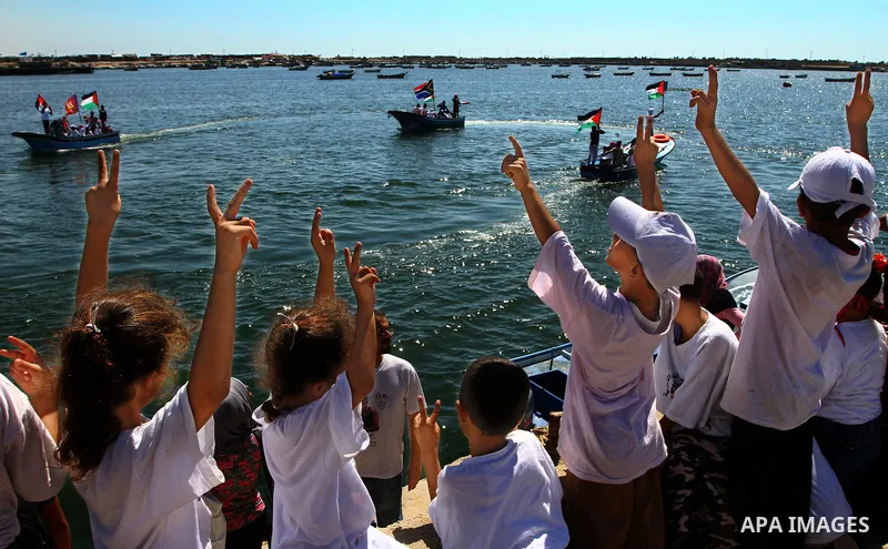Palestinian children wave Palestinian flags along with the national flags of activists taking part in the Gaza-bound international Freedom Flotilla hoping to breach Israel's sea blockade on Gaza during a rally in Gaza Ci...