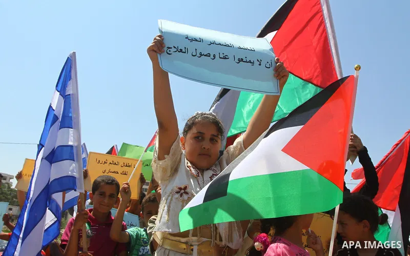 Palestinian children wave Palestinian and Greek flags during a rally in Gaza City in support of the international Freedom Flotilla hoping to breach Israel's sea blockade on Gaza as it remained banned by Greece from setti...