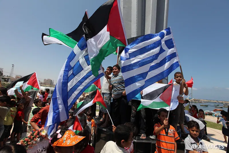 Palestinian children wave Palestinian and Greek flags during a rally in Gaza City in support of the international Freedom Flotilla hoping to breach Israel's sea blockade on Gaza as it remained banned by Greece from setti...