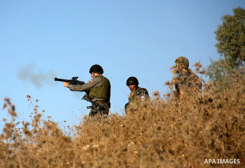 An Israeli soldier fires tear gas canister during clashes between Palestinians and settlers over farming land between the Jewish settlement of Yitzhar and the nearby West Bank village of Asira, near Nablus, Sunday, July...
