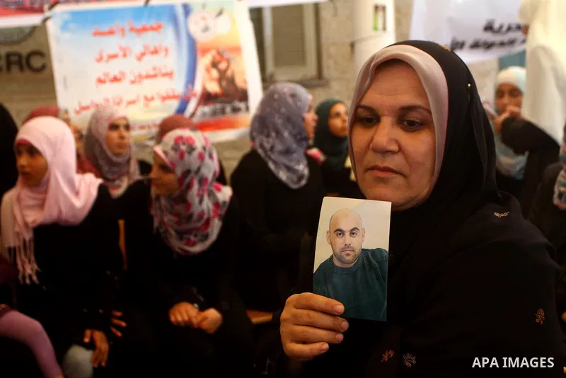 A Palestinian woman holds picture of her relative held in Israeli jails during a protest calling for their release in front of the Red Cross in Gaza city on July 4, 2011. Israel currently holds about 5,600 Palestinian pr...