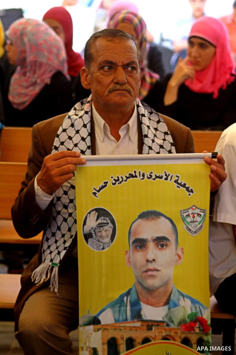 A Palestinian man holds picture of his relative held in Israeli jails during a protest calling for their release in front of the Red Cross in Gaza city on July 4, 2011. Israel currently holds about 5,600 Palestinian pris...