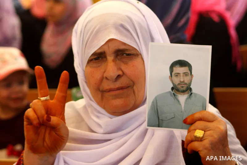 A Palestinian woman holds picture of her relative held in Israeli jails during a protest calling for their release in front of the Red Cross in Gaza city on July 4, 2011. Israel currently holds about 5,600 Palestinian pr...