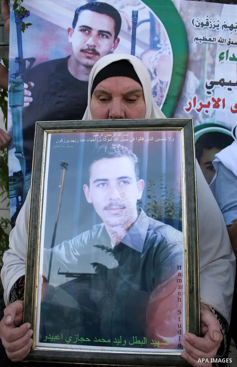 Palestinian relatives of Waleed Abedo hold his picture on July 4, 2011, in the West Bank town of Hebron, after Palestinian minister for civil affairs Hussein al-Sheikh announced that Israel is to release the bodies of 84...