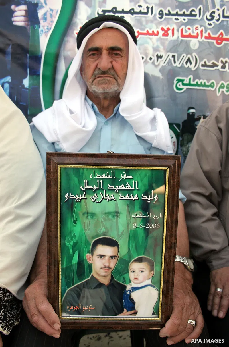 Palestinian relatives of Waleed Abedo hold his picture on July 4, 2011, in the West Bank town of Hebron, after Palestinian minister for civil affairs Hussein al-Sheikh announced that Israel is to release the bodies of 84...