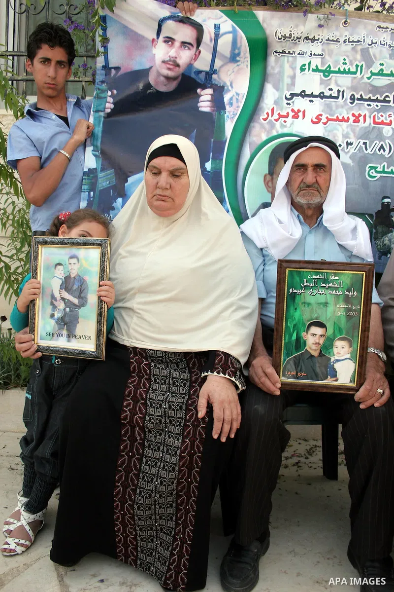 Palestinian relatives of Waleed Abedo hold his picture on July 4, 2011, in the West Bank town of Hebron, after Palestinian minister for civil affairs Hussein al-Sheikh announced that Israel is to release the bodies of 84...