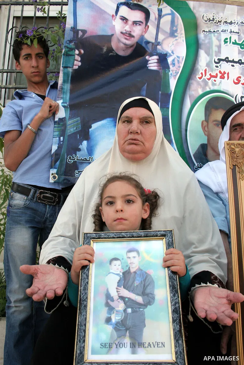 Palestinian relatives of Waleed Abedo hold his picture on July 4, 2011, in the West Bank town of Hebron, after Palestinian minister for civil affairs Hussein al-Sheikh announced that Israel is to release the bodies of 84...
