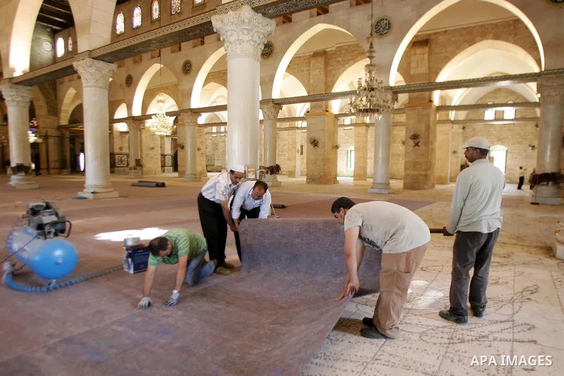 Palestinians fit rolls of new carpet inside the Al-Aqsa Mosque in Jerusalem's Old City on July 4, 2011. According to Sheikh Azzam Khatib, the head of the Islamic Waqf in Jerusalem, work have started to fit 5000 square me...