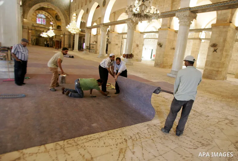 Palestinians fit rolls of new carpet inside the Al-Aqsa Mosque in Jerusalem's Old City on July 4, 2011. According to Sheikh Azzam Khatib, the head of the Islamic Waqf in Jerusalem, work have started to fit 5000 square me...