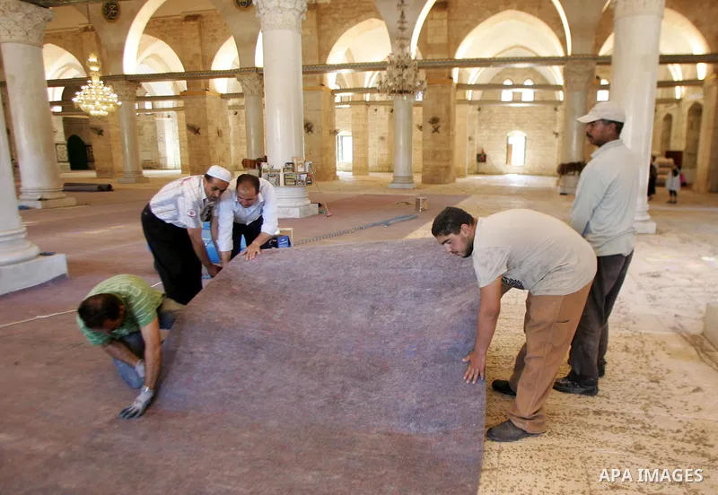 Palestinians fit rolls of new carpet inside the Al-Aqsa Mosque in Jerusalem's Old City on July 4, 2011. According to Sheikh Azzam Khatib, the head of the Islamic Waqf in Jerusalem, work have started to fit 5000 square me...