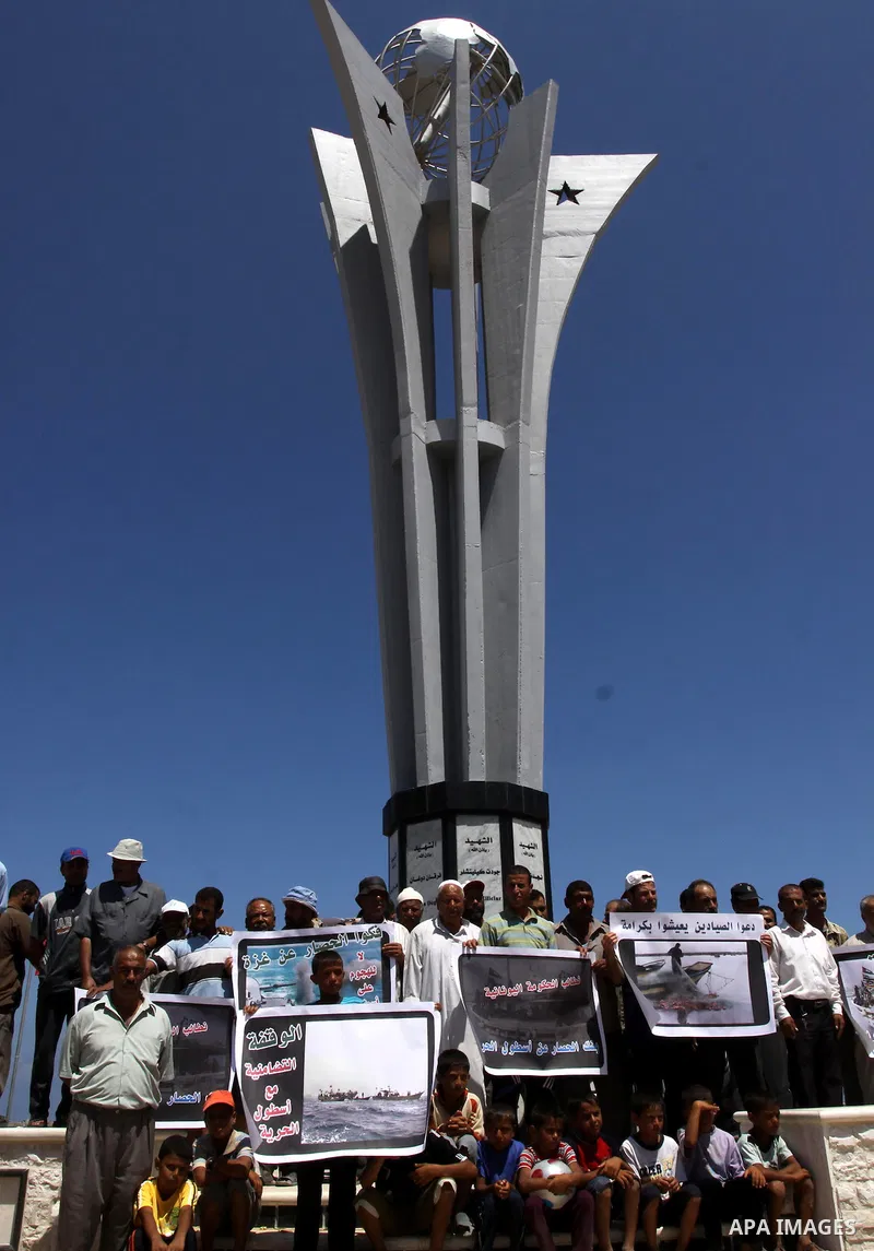 Palestinian fishermen and children hold banners during a rally in Gaza City in support of the international Freedom Flotilla hoping to breach Israel's sea blockade on Gaza as it remained banned by Greece from setting sai...