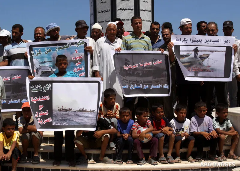 Palestinian fishermen and children hold banners during a rally in Gaza City in support of the international Freedom Flotilla hoping to breach Israel's sea blockade on Gaza as it remained banned by Greece from setting sai...