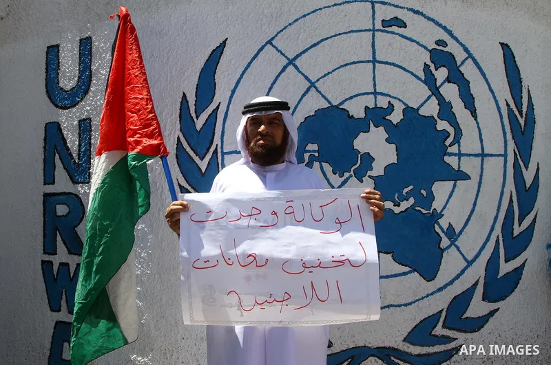 A Palestinian man holds the national flag during a protest in front of UNRWA headquarters in Gaza city on July 5, 2011. Dozens of Palestinians gather to protest against the UNRWA decision to change its name. Photo by Ash...