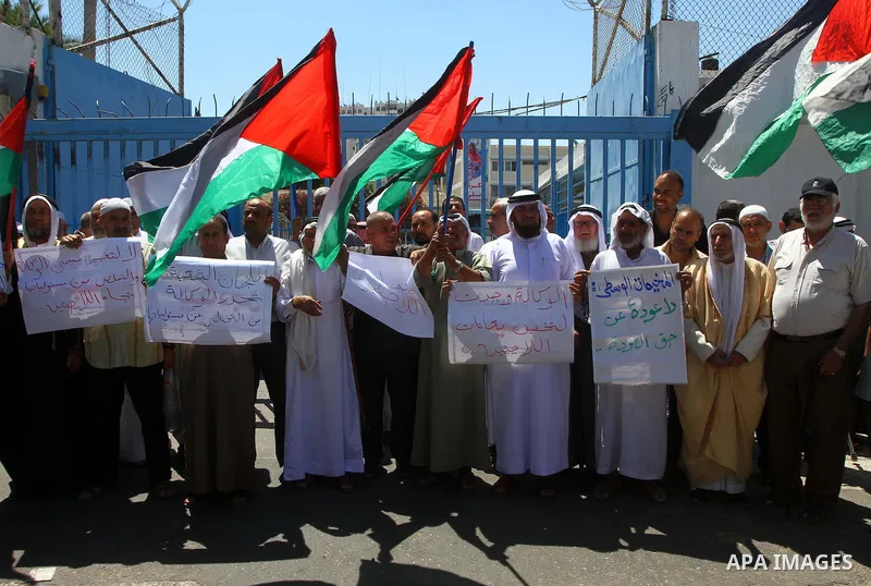 Palestinians hold their national flags during a protest in front of UNRWA headquarters in Gaza city on July 5, 2011. Dozens of Palestinians gather to protest against the UNRWA decision to change its name. Photo by Ashraf...