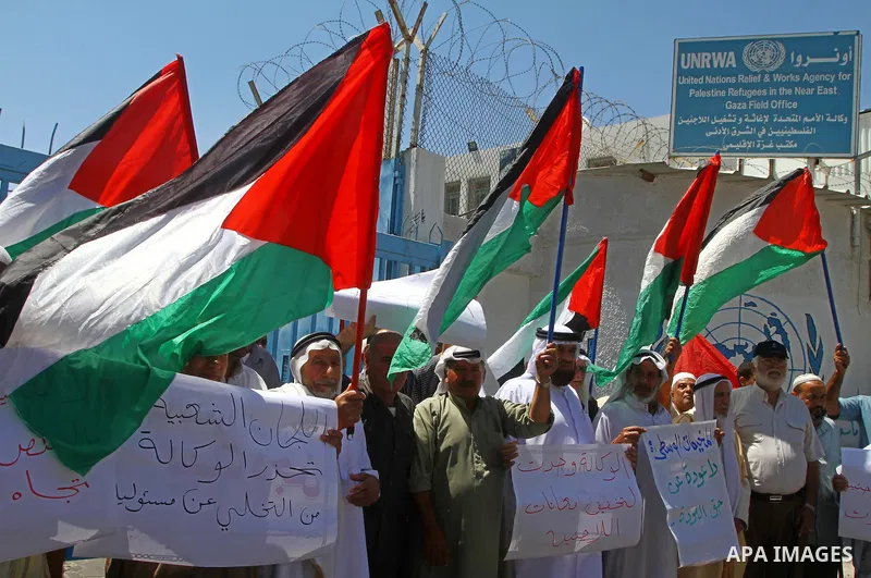 Palestinians hold their national flags during a protest in front of UNRWA headquarters in Gaza city on July 5, 2011. Dozens of Palestinians gather to protest against the UNRWA decision to change its name. Photo by Ashraf...