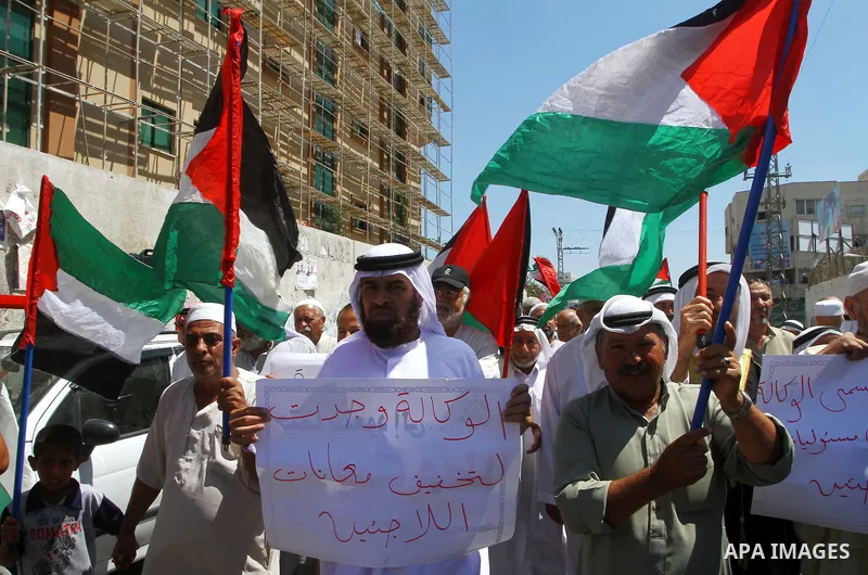 Palestinians hold their national flags during a protest in front of UNRWA headquarters in Gaza city on July 5, 2011. Dozens of Palestinians gather to protest against the UNRWA decision to change its name. Photo by Ashraf...