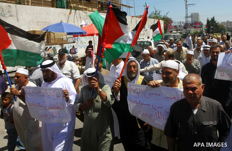 Palestinians hold their national flags during a protest in front of UNRWA headquarters in Gaza city on July 5, 2011. Dozens of Palestinians gather to protest against the UNRWA decision to change its name. Photo by Ashraf...