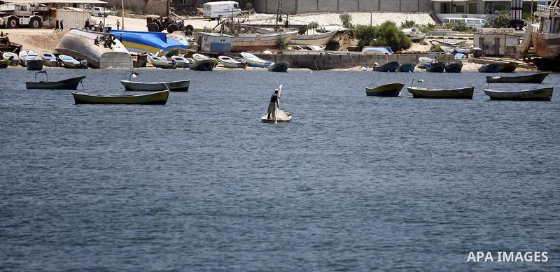 A Palestinian fisherman works on his boat in the port of Gaza City, Tuesday, July 5, 2011, as pro-Palestinian activists from an international flotilla banned from setting sail for Gaza by Greek authorities occupied the S...
