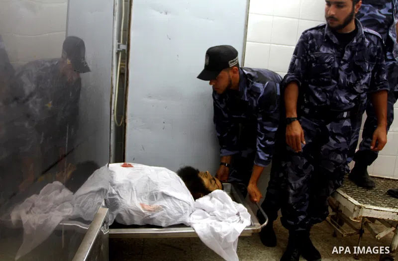 Hamas security officers stand next to bodies of two Palestinians killed by Israeli forces, at the morgue of Al-Aqsa hospital in Deir Al Balah, central Gaza Strip, Tuesday, July 5, 2011. An Israeli attack struck a target...