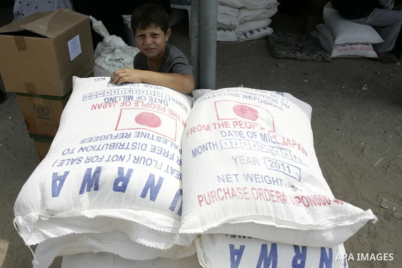 A Palestinianboy receives humanitarian aid with his family at the United Nations aid distribution centre in the refugee camp of Rafah in the southern Gaza Strip on July 7, 2011. United Nations Relief and Works Agency (UN...