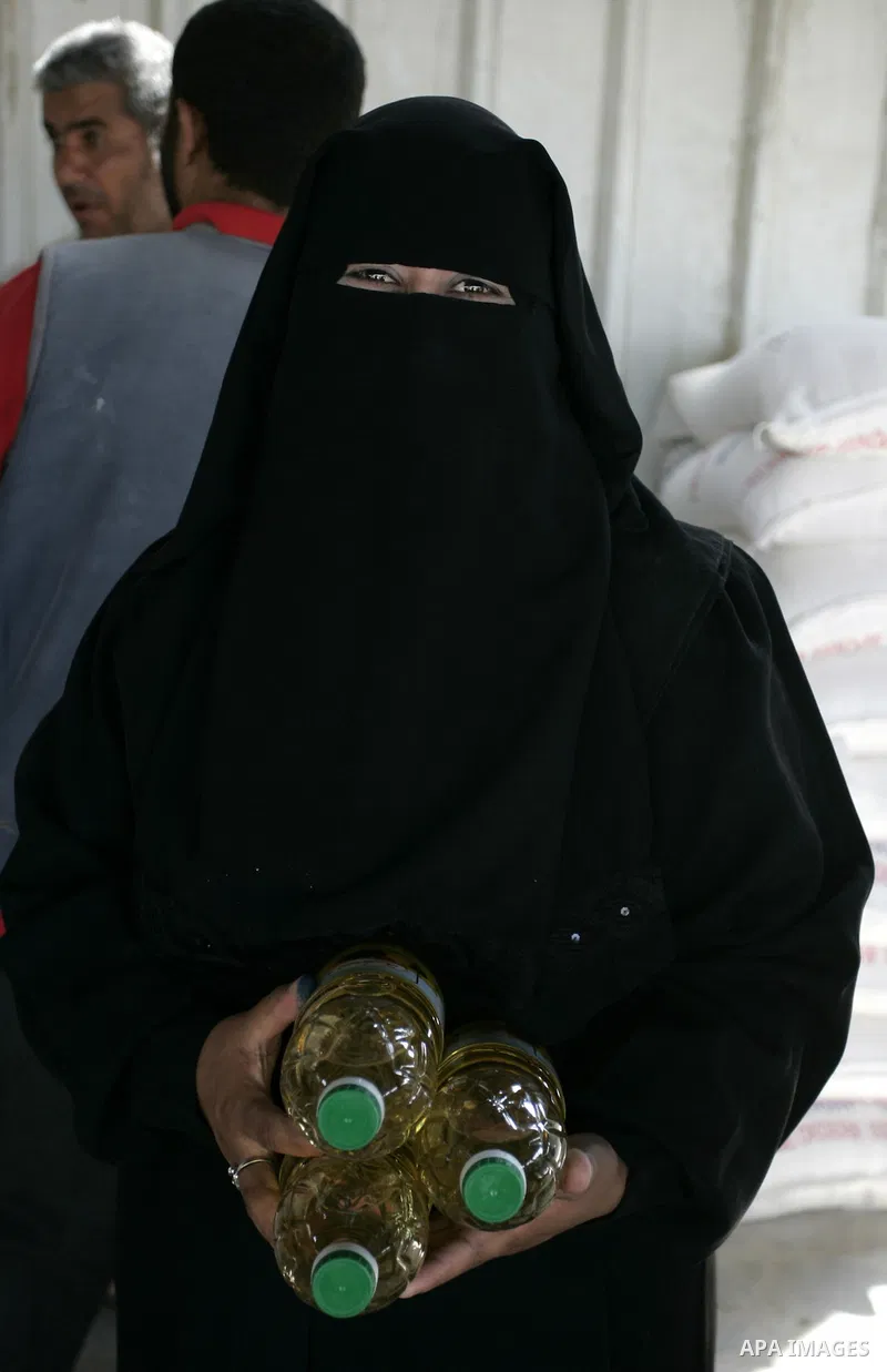 A Palestinian woman receives humanitarian aid at the United Nations aid distribution centre in the refugee camp of Rafah in the southern Gaza Strip on July 7, 2011. United Nations Relief and Works Agency (UNRWA) decide t...