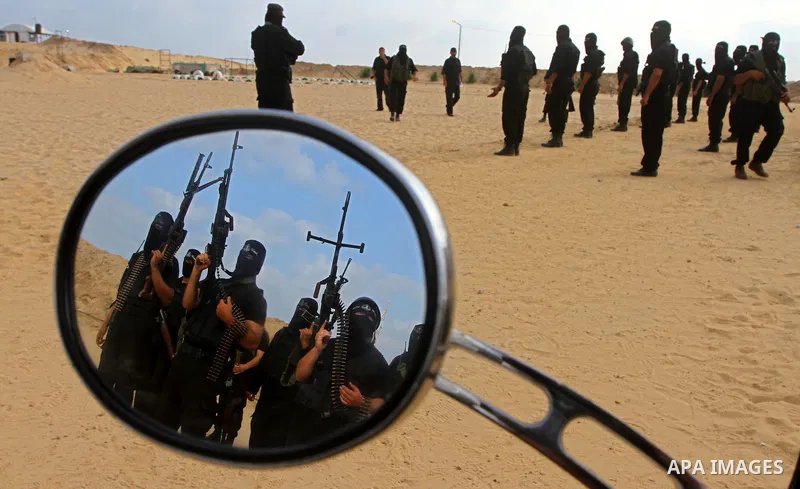 Some Palestinian militants from Al-Ansar brigades, the armed wing of Al-Ahrar movement, are reflected the mirror of a motorcycle as they demonstrate their skills during a drill in front of the media in Khan Younis in the...