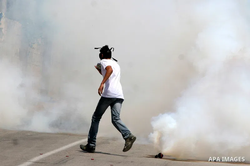 A Palestinian protester from the West Bank village of Nabi Salih, north of Ramallah, try to avoid tear gas shot by Israeli soldiers, on 08 July 2011, as they stand next to a symbolic flotilla boat, during the weekly Frid...