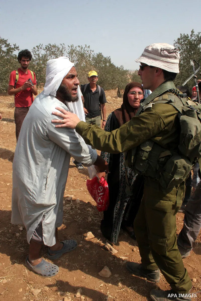 An Israeli soldier scuffles with Palestinian, foreign and Israeli protesters during a demonstration against the demolishing of farm land to be used in the construction of Jewish settlements near the existing Israeli sett...