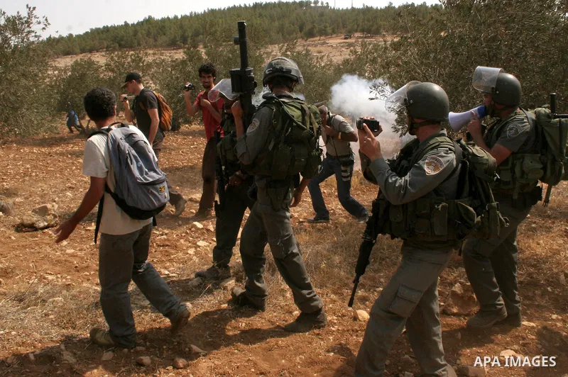 Palestinian, foreign and Israeli protesters run for cover as Israeli troops fire tear gas to disperse the protesters during a demonstration against the demolishing of farm land to be used in the construction of Jewish se...
