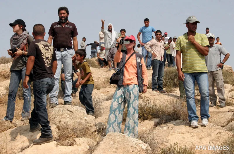 Palestinian, foreign and Israeli protesters take part in a demonstration against the demolishing of farm land to be used in the construction of Jewish settlements near the existing Israeli settlement of Maaon near the Pa...