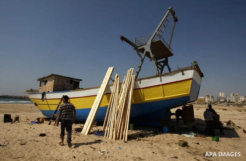 Palestinian fishermen repair their boat on Gaza city beach on July 10,2011. Photo by Mahmoud Nassar