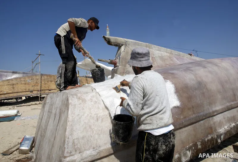 Palestinian fishermen repair their boat on Gaza city beach on July 10,2011. Photo by Mahmoud Nassar