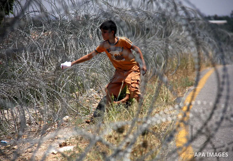 A protestor tries to remove a part of Israeli separation barrier during a demonstration by Palestinian and foreign activists against Israeli occupation and settlements on July 11, 2011 in the village of Ezbet Tabeeb near...