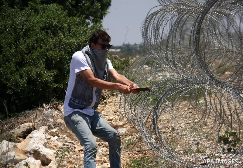 A protestor tries to remove a part of Israeli separation barrier during a demonstration by Palestinian and foreign activists against Israeli occupation and settlements on July 11, 2011 in the village of Ezbet Tabeeb near...