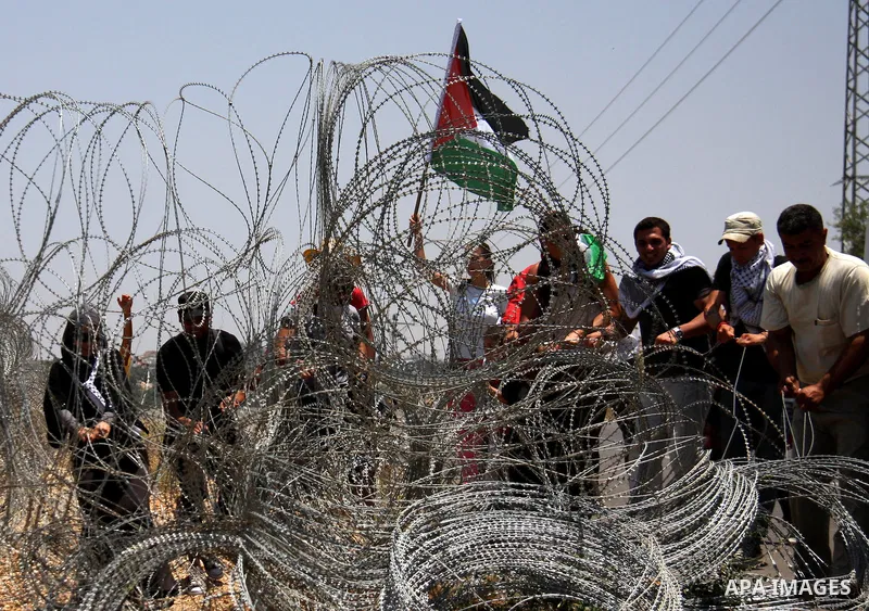 Palestinian and foreign protesters try to remove a part of Israeli separation barrier during a demonstration against Israeli occupation and settlements on July 11, 2011 in the village of Ezbet Tabeeb near the West Bank t...