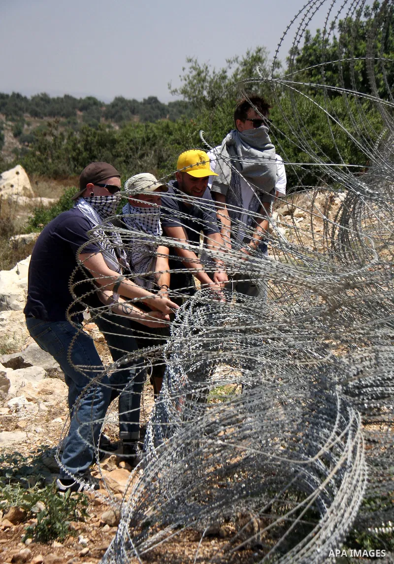 Palestinian and foreign protesters try to remove a part of Israeli separation barrier during a demonstration against Israeli occupation and settlements on July 11, 2011 in the village of Ezbet Tabeeb near the West Bank t...