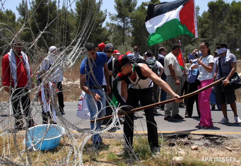 Palestinian and foreign protesters try to remove a part of Israeli separation barrier during a demonstration against Israeli occupation and settlements on July 11, 2011 in the village of Ezbet Tabeeb near the West Bank t...