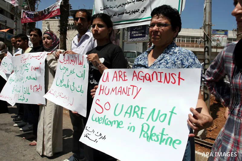 Palestinians hold signs against the visit by Greek President Karolos Papoulias to the West Bank during a protest in Ramallah on July 12, 2011. Papoulias met Palestinian Authority President Mahumud Abbas today in the West...