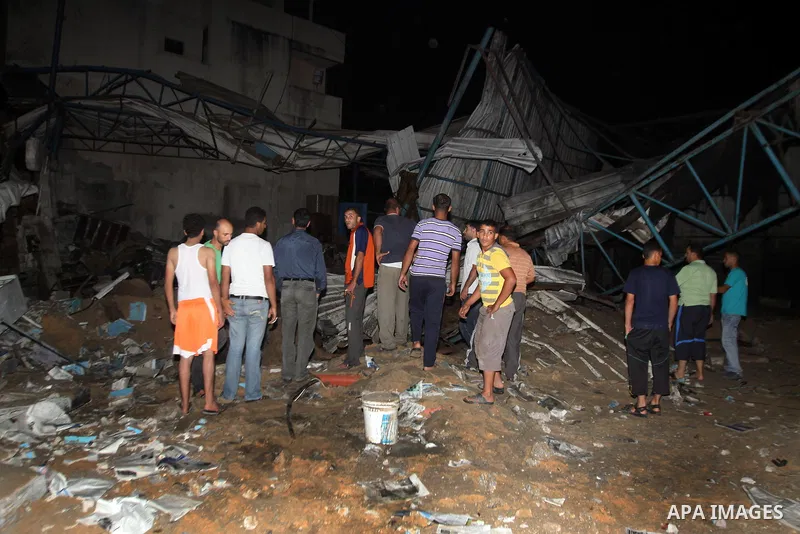 Palestinians inspect debris in a destroyed car wash garage after Israeli airstrike in the Al Tuffah area in the east of Gaza City, in the Gaza Strip on 12 July 2011. Photo by Ali Jadallh