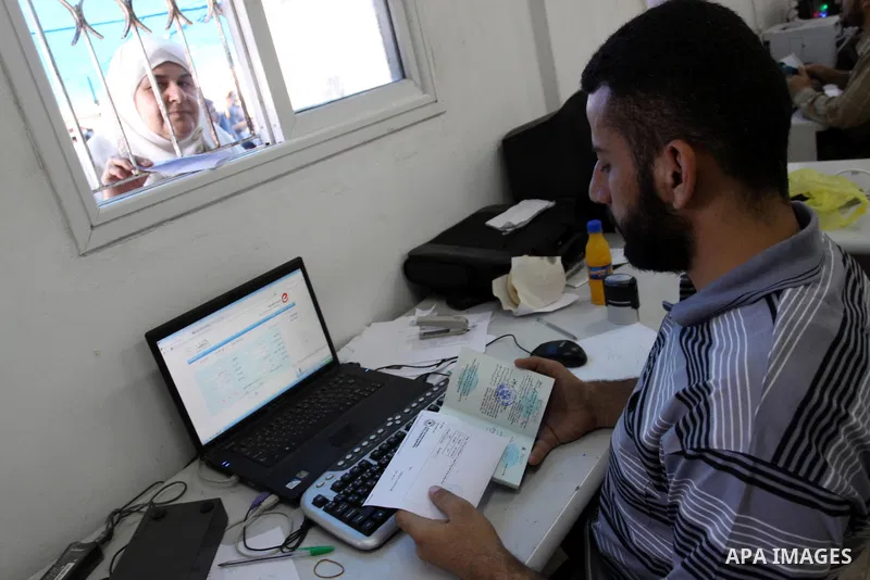Palestinians wait behind the window to register their names with the Ministry of the Interior in the lists of travel in Gaza city on July 13, 2011. Where there are more than 20 thousand citizens need to travel abroad, Th...