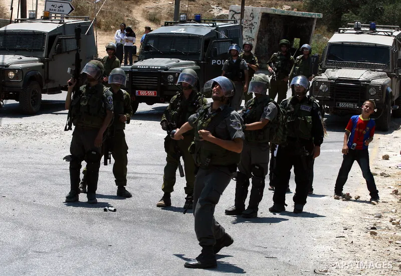 An Israeli soldier hurls tear gas canister toward Palestinian protestors during clashes following a demonstration against Israeli occupation and settlements expansion, on July 15, 2011 in the West Bank village of Nabi Sa...