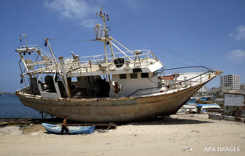A Palestinian child walk near a boat at Gaza beach on July 16,2011. Photo by Mahmoud Nassar