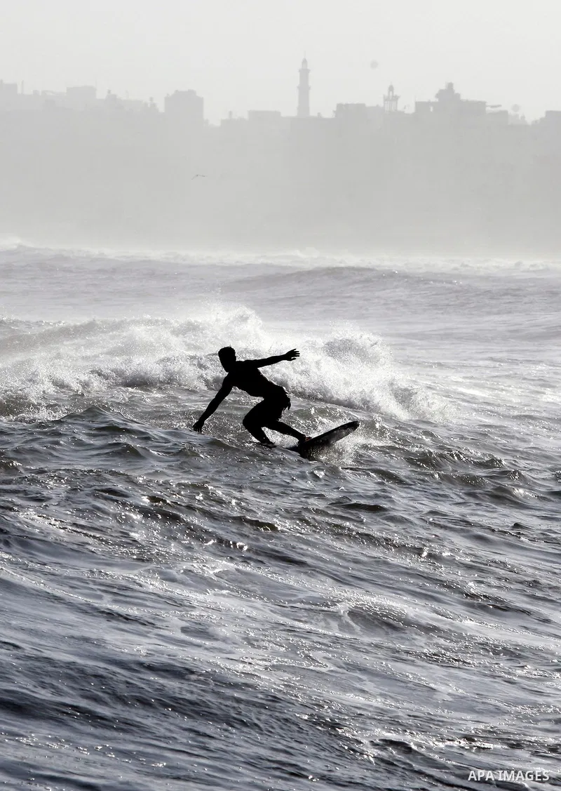 A Palestinian surfer rides a wave during a practise session in Gaza City on July 17, 2011 . Photo by Mahmud Nassar