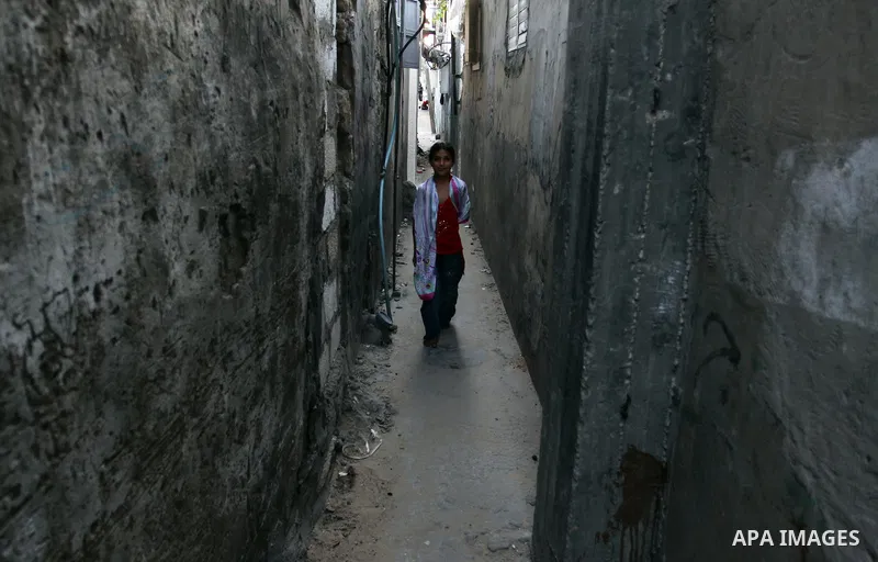 A Palestinian girl walks out from her house window in the Jabaliya refugee camp in the northern area of the Gaza Strip on July 21, 2011. The UN Relief and Works Agency (UNRWA) will reduce some of its services for Palesti...