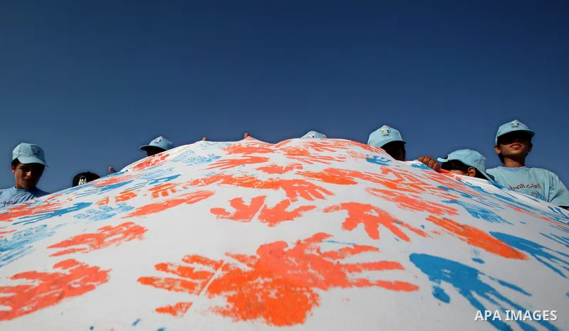 Palestinian children attend an event organised by the the United Nations Relief and Works Agency (UNRWA) in which they attempt to break the Guinness world record for the largest hand-print paint in Khan Yunis, southern G...