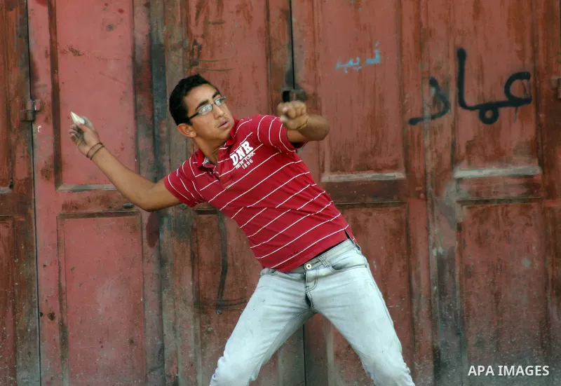 A Palestinian protester hurls stones toward Israeli soldiers during a demonstration by Palestinian, Israeli, and foreign protesters in the West Bank village of Beit Omar, near Hebron Friday, July 22, 2011. The demonstrat...