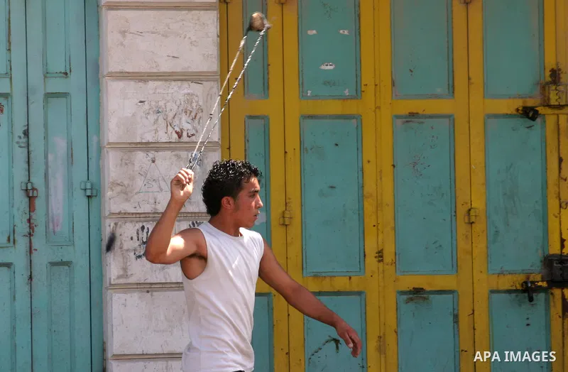A Palestinian protester hurls stones toward Israeli soldiers during a demonstration by Palestinian, Israeli, and foreign protesters in the West Bank village of Beit Omar, near Hebron Friday, July 22, 2011. The demonstrat...