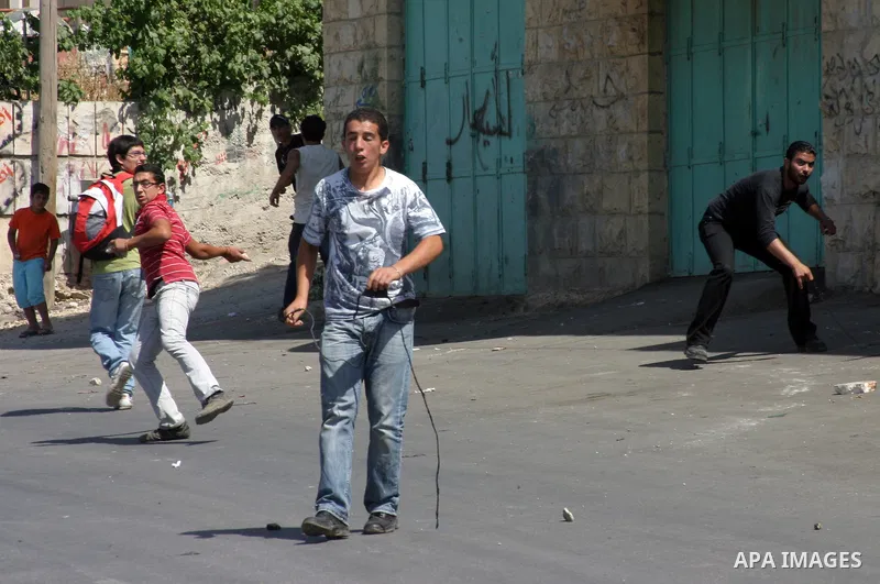 A Palestinian protester hurls stones toward Israeli soldiers during a demonstration by Palestinian, Israeli, and foreign protesters in the West Bank village of Beit Omar, near Hebron Friday, July 22, 2011. The demonstrat...