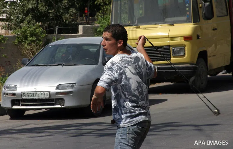 A Palestinian protester hurls stones toward Israeli soldiers during a demonstration by Palestinian, Israeli, and foreign protesters in the West Bank village of Beit Omar, near Hebron Friday, July 22, 2011. The demonstrat...