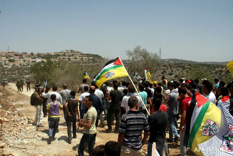 Palestinian protestors take part in a demonstration by against the closure of a road during the second Intifada by Jewish settlers from the nearby settlement of Kadumim , on July 22, 2011 in the West Bank village of Kfar...